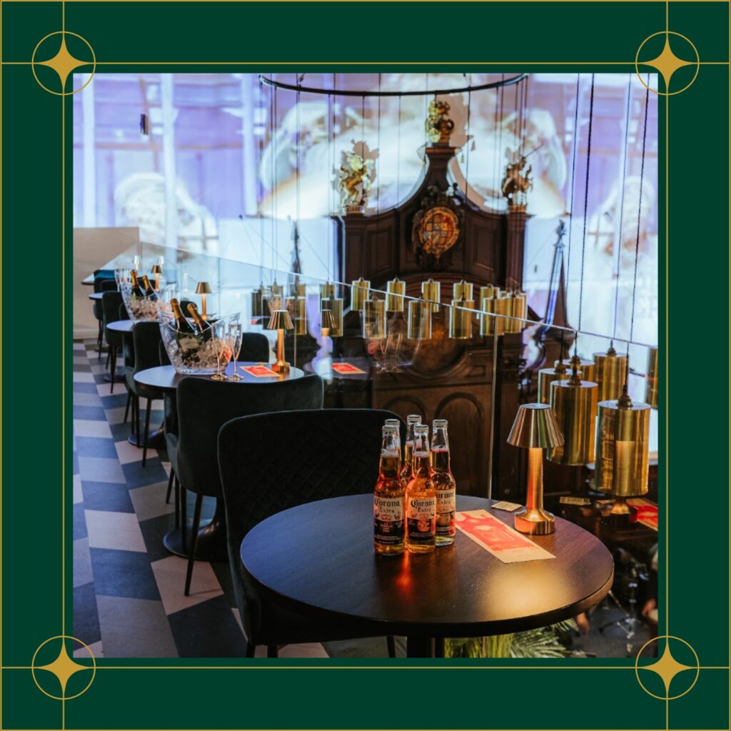 A cozy restaurant in Amazing Grace London, featuring tables, chairs, and bottles of beer on display.