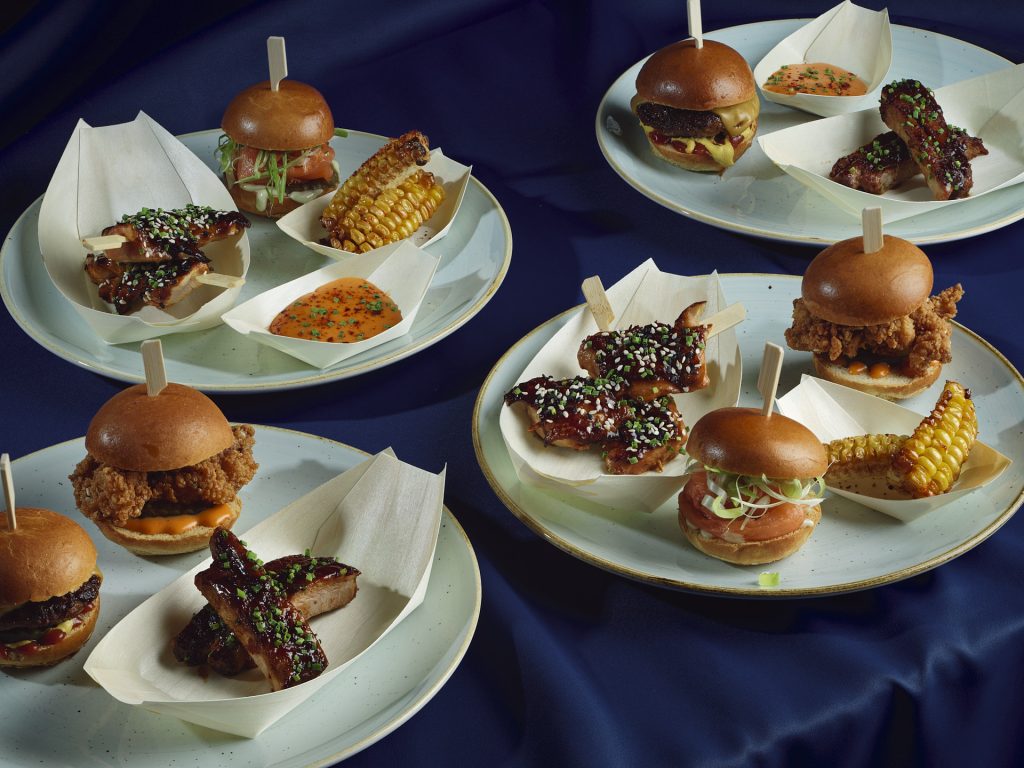 Amazing Grace London served burgers, glazed chicken wings, corn on the cob, and dipping sauce, creating a luxurious feast.